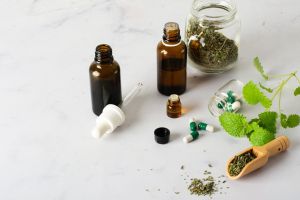 Na zdjęciu na stole poukładane zioła, tabletki, fiolki, lekarstwa. 